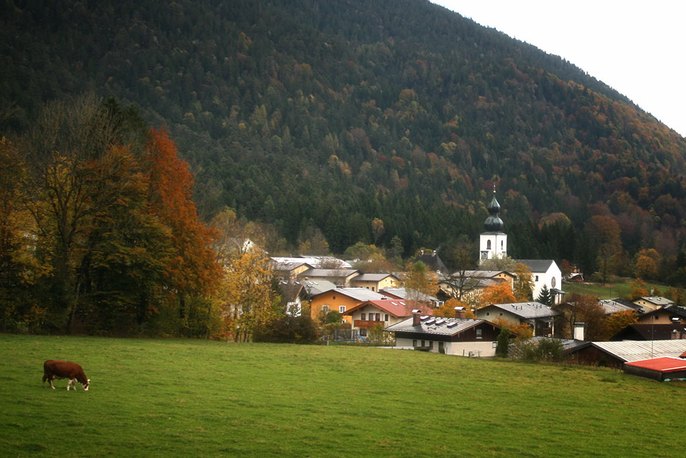 Häuser vor dem Berg mit Kirche und bunten Bäumen
